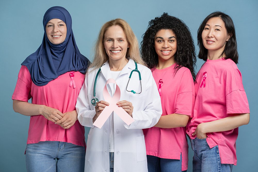 Doctor, diverse multinational patients smiling and showing pink ribbon for breast cancer awareness
